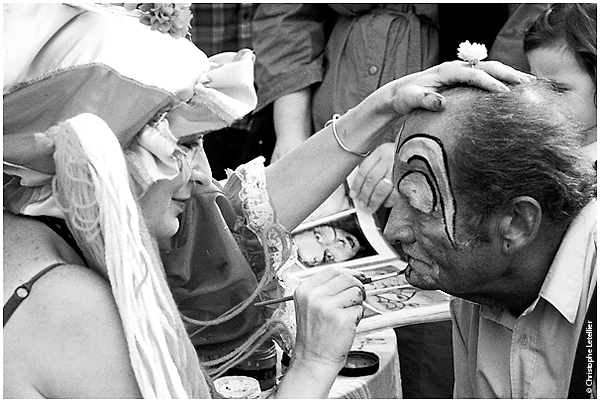 Photo noir et blanc "visage de clown". A Granville, une maquilleuse professionnelle effectue,sous le regard amusé des enfants et des touristes, un maquillage de clown sur le visage d'un vieil homme.© 2010 Christophe Letellier tous droits réservés. Pour revenir à la galerie, cliquez sur la photo.